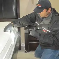 Bed bug inspection technician checking a mattress and bed frame for signs of infestation in Knoxville, TN