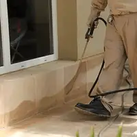 General pest control technician spraying exterior perimeter around a home in Knoxville, TN